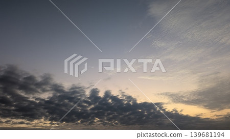 A serene dawn sky with a crescent moon above a bank of dark clouds. The sky transitions from light blue to a warm golden hue near the horizon. It's a peaceful scene of natural beauty. A serene dawn sky with a crescent moon above a bank of dark clouds. The sky transitions from light blue to a warm golden hue near the horizon. It's a peaceful scene of natural beauty. 139681194