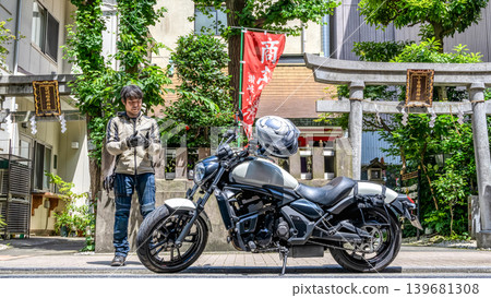 一名騎摩托車的男子在讚岐小梅稻荷神社前看著他的智慧型手機。 139681308