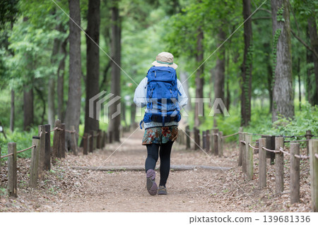 A woman enjoying a healthy outdoor lifestyle, walking and taking in the scenery of a lush green forest while hiking and climbing (faceless). A woman enjoying a healthy outdoor lifestyle, walking and taking in the scenery of a lush green forest while hiking and climbing (faceless). 139681336