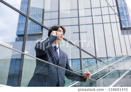 A businessman answering the phone on an outdoor staircase in a city building - a sales scene. A businessman answering the phone on an outdoor staircase in a city building - a sales scene. 139681435