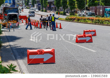 Traffic control and arrow directional signs at a road construction site, and a person directing pedestrians. Traffic control and arrow directional signs at a road construction site, and a person directing pedestrians. 139681569