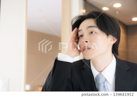 A businessman checking his hair and appearance in the hotel mirror in the morning – a pre-business check image for job interviews or business trips. A businessman checking his hair and appearance in the hotel mirror in the morning – a pre-business check image for job interviews or business trips. 139681952