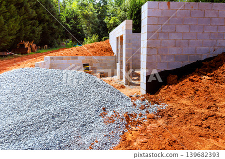 Construction work on new building site with gravel cinder blocks near trees Construction work on new building site with gravel cinder blocks near trees 139682393