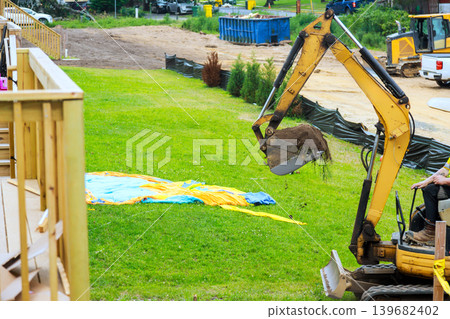 Construction project involves machinery moving soil in yard at residential site Construction project involves machinery moving soil in yard at residential site 139682402