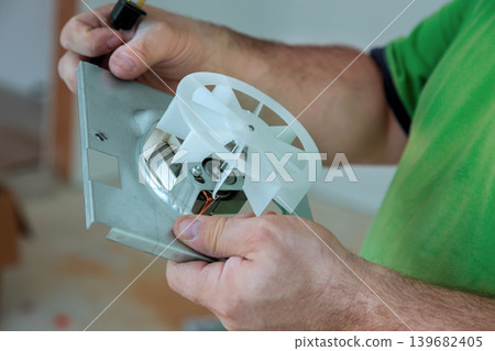 Person works on cooling fan inside mechanical device in workshop Person works on cooling fan inside mechanical device in workshop 139682405