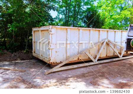 Large white dumpster placed in wooded area for waste collection Large white dumpster placed in wooded area for waste collection 139682430