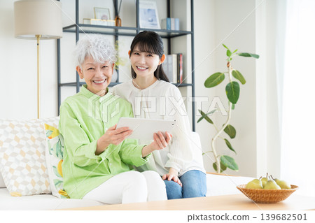 Senior parent and child using a tablet in the living room 139682501