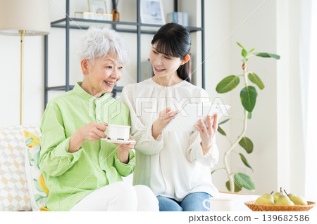 A senior mother and her middle-aged daughter relaxing in the living room. 139682586