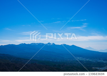 A vivid view of the snow-capped Yatsugatake mountain range from Kirigamine, with Mount Fuji towering in the far right background. A vivid view of the snow-capped Yatsugatake mountain range from Kirigamine, with Mount Fuji towering in the far right background. 139683694