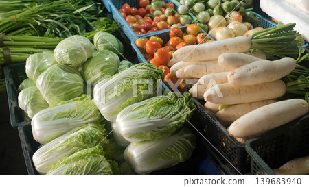 Market stall counter packed with colorful assorted vegetables including cabbage, tomatoes, daikon, chili, lime, Thai basil, cucumbers, eggplants, beans and Chinese cabbage. Fresh market concept Market stall counter packed with colorful assorted vegetables including cabbage, tomatoes, daikon, chili, lime, Thai basil, cucumbers, eggplants, beans and Chinese cabbage. Fresh market concept 139683940