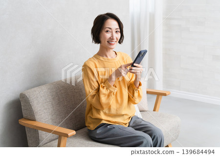 Woman operating a smartphone Lifestyle image Woman operating a smartphone Lifestyle image 139684494