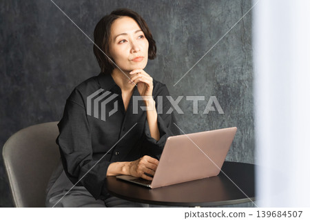 Woman using a laptop at a table Lifestyle image Woman using a laptop at a table Lifestyle image 139684507
