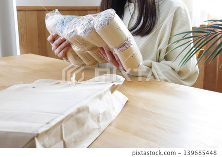 一位女士在燈光明亮的房間裡看著毛線。 一位女士在燈光明亮的房間裡看著毛線。 139685448