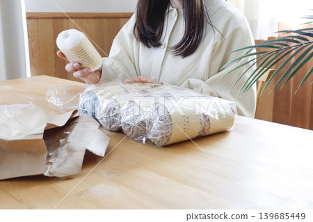 一位女士在燈光明亮的房間裡看著毛線。 一位女士在燈光明亮的房間裡看著毛線。 139685449