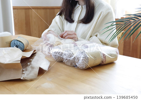 一位女士在燈光明亮的房間裡看著毛線。 139685450