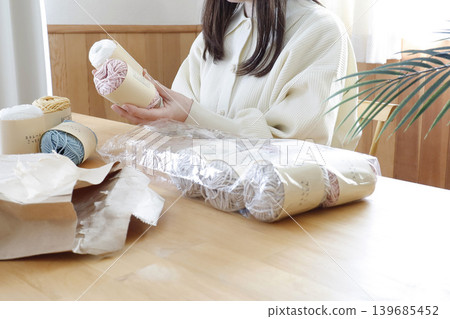一位女士在燈光明亮的房間裡看著毛線。 一位女士在燈光明亮的房間裡看著毛線。 139685452