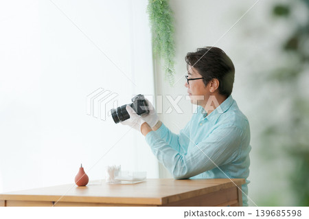 A man cleaning a single-lens reflex camera. 139685598