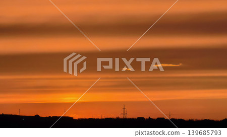 Orange sunset sky over horizon with silhouettes and clouds Orange sunset sky over horizon with silhouettes and clouds 139685793