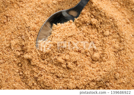 Spoon filled with raw brown sugar in heap of granulated crystals Spoon filled with raw brown sugar in heap of granulated crystals 139686922