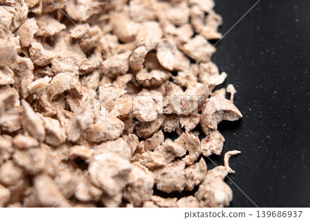 Scattered particles of biodegradable vegetable cat litter on a black surface. Macro 139686937