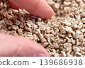 Close up of fingers picking up plant based cat litter granules with dry porous texture and lightweight structure. Absorbent material 139686938