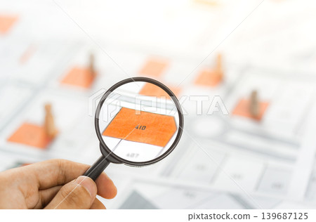 Man holding magnifier on cadastre map search for assesses to buy the land lands. real estate concept with vacant land for building construction and housing subdivision for sale, rent, buy, investment. Man holding magnifier on cadastre map search for assesses to buy the land lands. real estate concept with vacant land for building construction and housing subdivision for sale, rent, buy, investment. 139687125