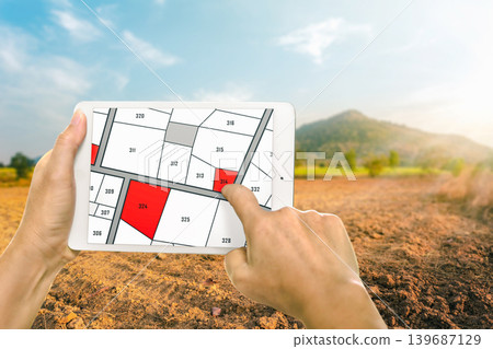 Man holding a tablet looking at lots of lands. Land plot management - real estate concept with vacant land for building construction and housing subdivision for sale, rent, buy, or investment. Man holding a tablet looking at lots of lands. Land plot management - real estate concept with vacant land for building construction and housing subdivision for sale, rent, buy, or investment. 139687129