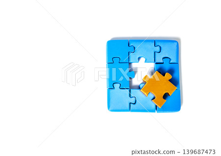 Blue jigsaw puzzle pieces arranged in a square with a missing center piece on white background. A single Gold piece sits on top, representing a unique solution or the final step in a concept. Blue jigsaw puzzle pieces arranged in a square with a missing center piece on white background. A single Gold piece sits on top, representing a unique solution or the final step in a concept. 139687473