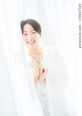 A Japanese woman in her 30s wrapped in a curtain. 139687589