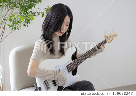 A woman who enjoys playing musical instruments, specifically the bass guitar. A woman who enjoys playing musical instruments, specifically the bass guitar. 139688247