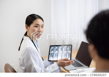 A Japanese female doctor in a white coat examines a male patient. A Japanese female doctor in a white coat examines a male patient. 139689207