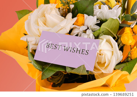 Close up of a vibrant floral gift. White roses, yellow blossoms, and green leaves are wrapped in yellow paper Close up of a vibrant floral gift. White roses, yellow blossoms, and green leaves are wrapped in yellow paper 139689251