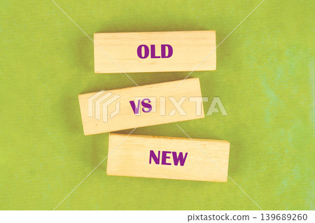 Wooden blocks arranged on a textured green surface show the words OLD, VS, NEW. This arrangement visually presents the concept of opposition, progress, and change Wooden blocks arranged on a textured green surface show the words OLD, VS, NEW. This arrangement visually presents the concept of opposition, progress, and change 139689260