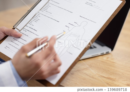 A close-up of a female doctor's hands as she fills out a medical chart. A close-up of a female doctor's hands as she fills out a medical chart. 139689718
