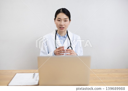 一位身穿白大褂的日本女醫生正在電腦上進行線上問診。 139689988