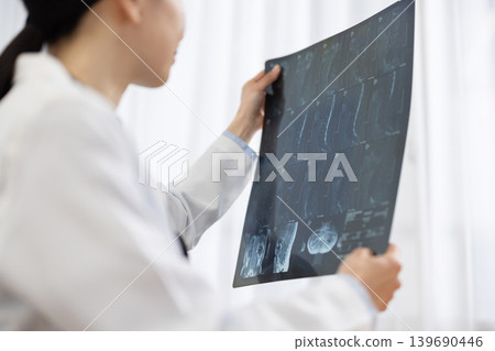 一位身穿白大褂的日本女醫生正在檢查X光片。 139690446