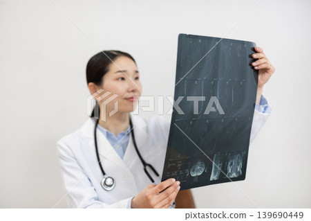 一位身穿白大褂的日本女醫生正在檢查X光片。 139690449