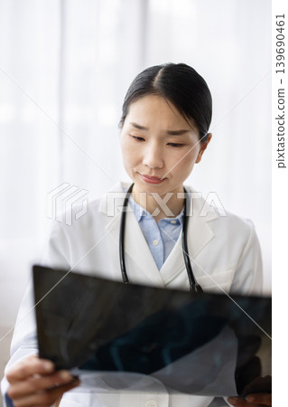 A Japanese female doctor in a white coat looking at X-ray images. A Japanese female doctor in a white coat looking at X-ray images. 139690461