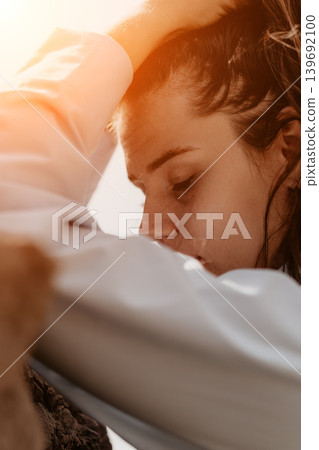 Woman portrait sunlight close up of a young female resting her head on her arms outdoors during golden hour sunset 139692100