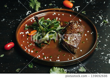 Gourmet steak plated with greens, tomatoes, and garnish Gourmet steak plated with greens, tomatoes, and garnish 139692686