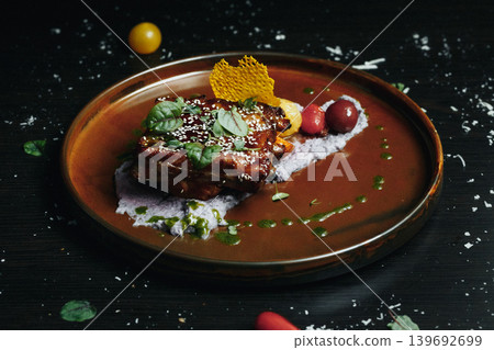 Served gourmet dish on rustic brown plate with vibrant garnishes and sauce Served gourmet dish on rustic brown plate with vibrant garnishes and sauce 139692699