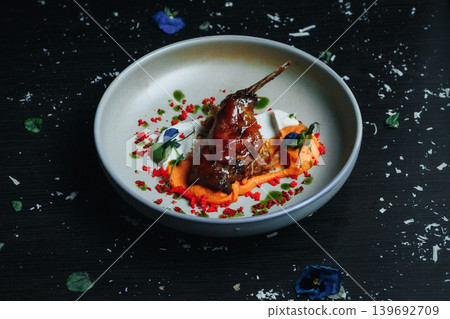 Duck breast elegantly plated with sauce and edible flowers on a dark background 139692709