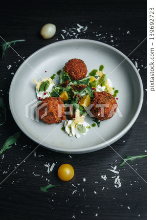 Croquettes with herb sauce and cherry tomatoes on dark table Croquettes with herb sauce and cherry tomatoes on dark table 139692723