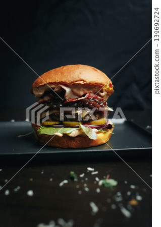 Delicious burger with bacon and lettuce on a black plate 139692724