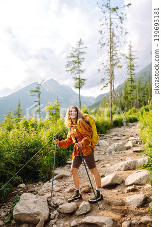 Young woman traveler hiking poles on trail among the mountains. Hiking. Active lifestyle. 139693181