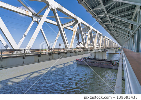 中國高速列車跨越河流的鋼桁架鐵路橋和水路運輸的場景。 中國高速列車跨越河流的鋼桁架鐵路橋和水路運輸的場景。 139693433