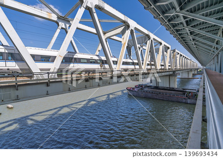 中國高速列車跨越河流的鋼桁架鐵路橋和水路運輸的場景。 139693434