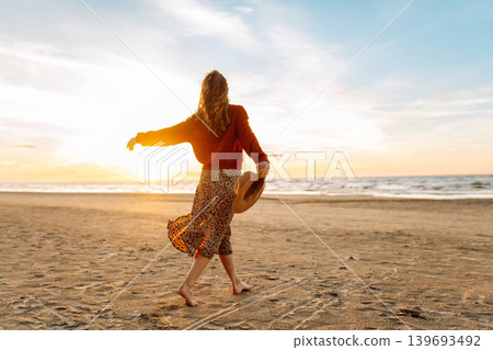 Beautiful woman on the beach in cold weather enjoying time in the sunset. Lifestyle, adventure. Beautiful woman on the beach in cold weather enjoying time in the sunset. Lifestyle, adventure. 139693492