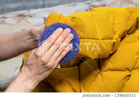 Hands gently wipe the yellow jacket with a microfiber pad. Hands gently wipe the yellow jacket with a microfiber pad. 139693532