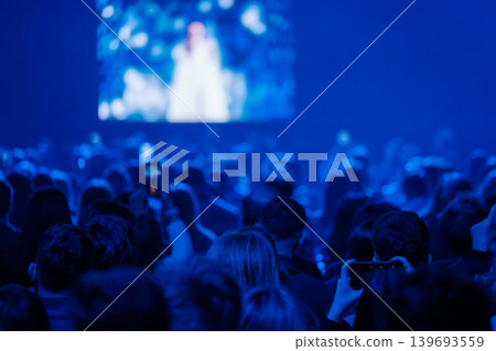 Blue concert audience watching stage performance, crowd recording with phones in dark venue Blue concert audience watching stage performance, crowd recording with phones in dark venue 139693559